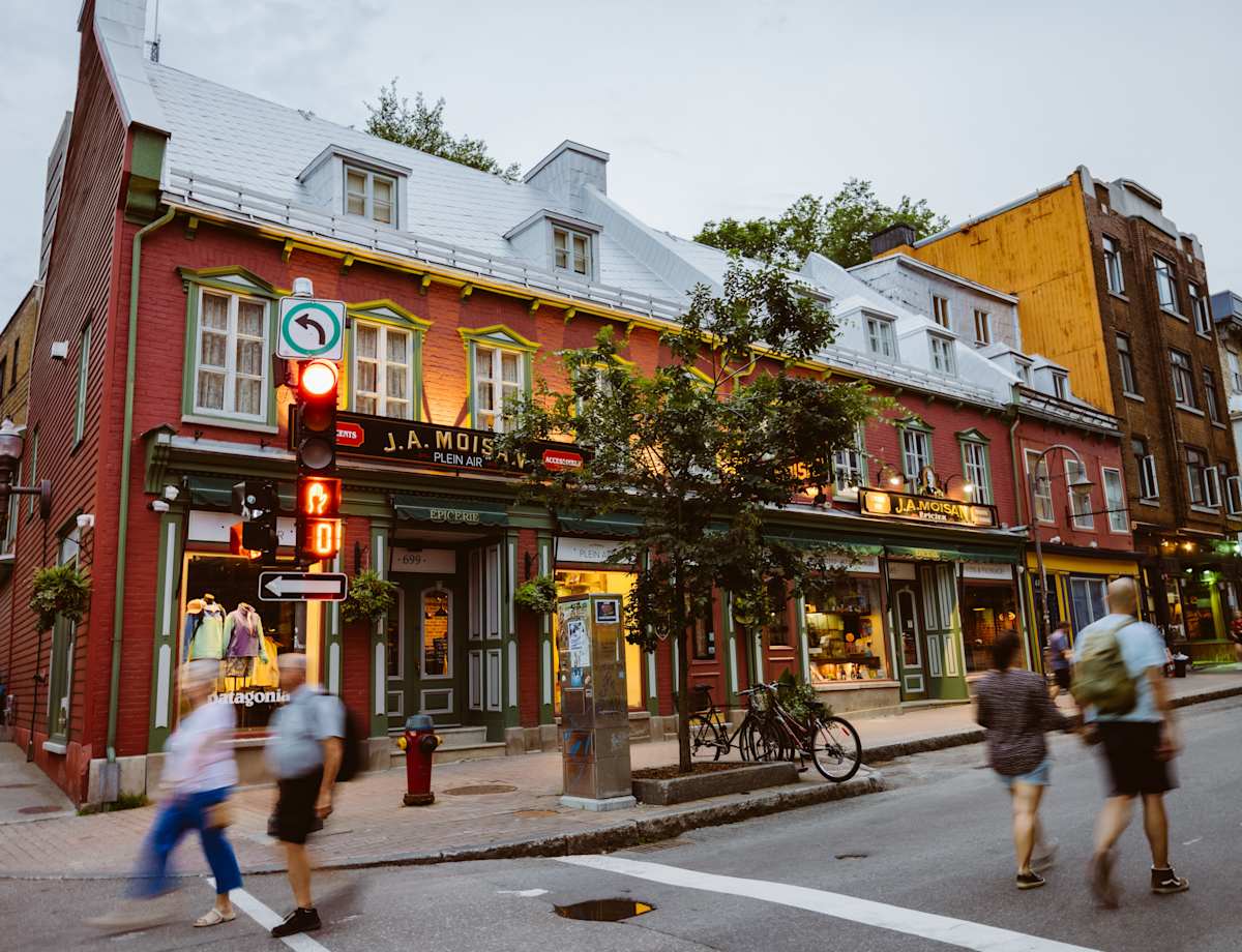 Une scène de rue animée et colorée, mêlant architecture traditionnelle et moderne, grouillante de piétons et de cyclistes au premier plan.