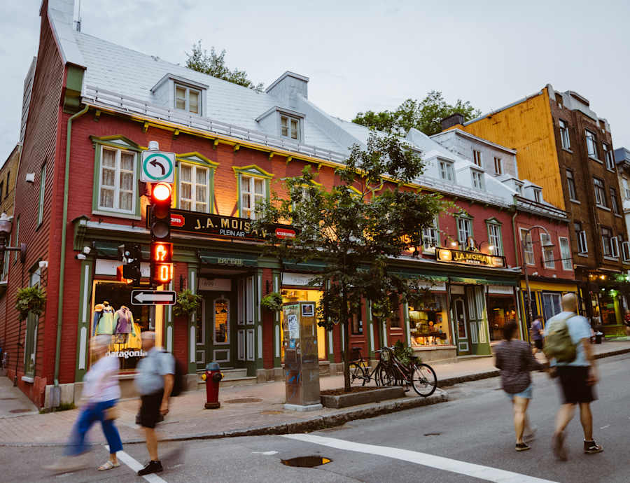Une scène de rue animée et colorée, mêlant architecture traditionnelle et moderne, grouillante de piétons et de cyclistes au premier plan.