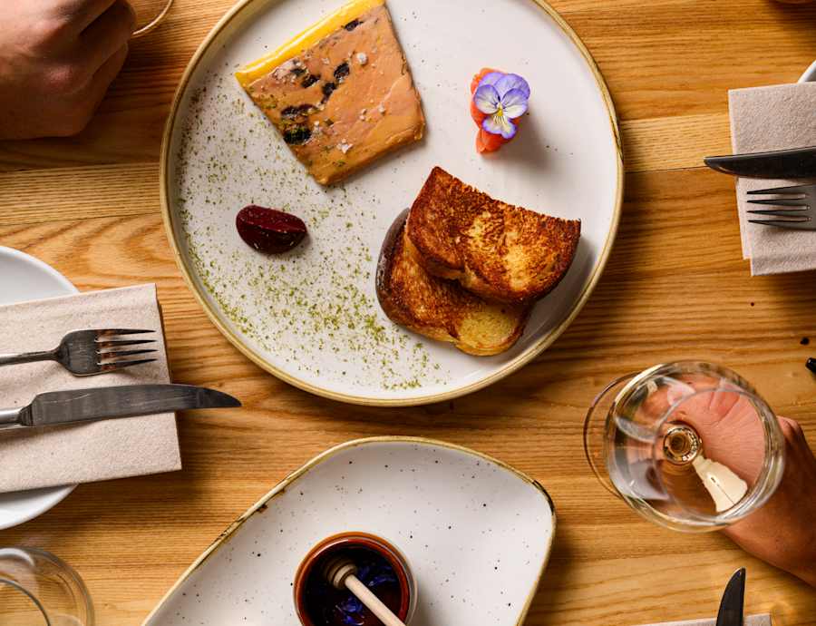 Deux assiettes de haute gastronomie avec pâtisseries, fromages et jus de fruit sur table en bois lors d'un repas